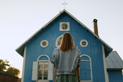 穿着灰色衬衫的女人站在蓝白相间的木屋前
